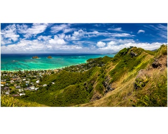 May include: A panoramic view from a mountaintop overlooking a turquoise ocean with two small islands in the distance. Lush green vegetation covers the mountainside, with a small town visible in the foreground.