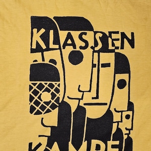 May include: Yellow t-shirt with a black graphic design of abstract faces and the text "KLASSEN KAMPF FWS".