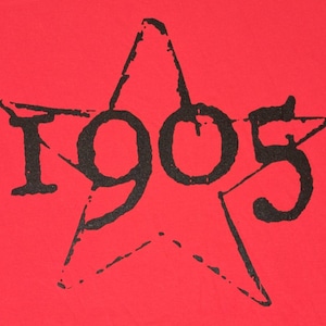 Peut inclure: Un t-shirt rouge avec une étoile noire et le nombre 1905 imprimé dessus.