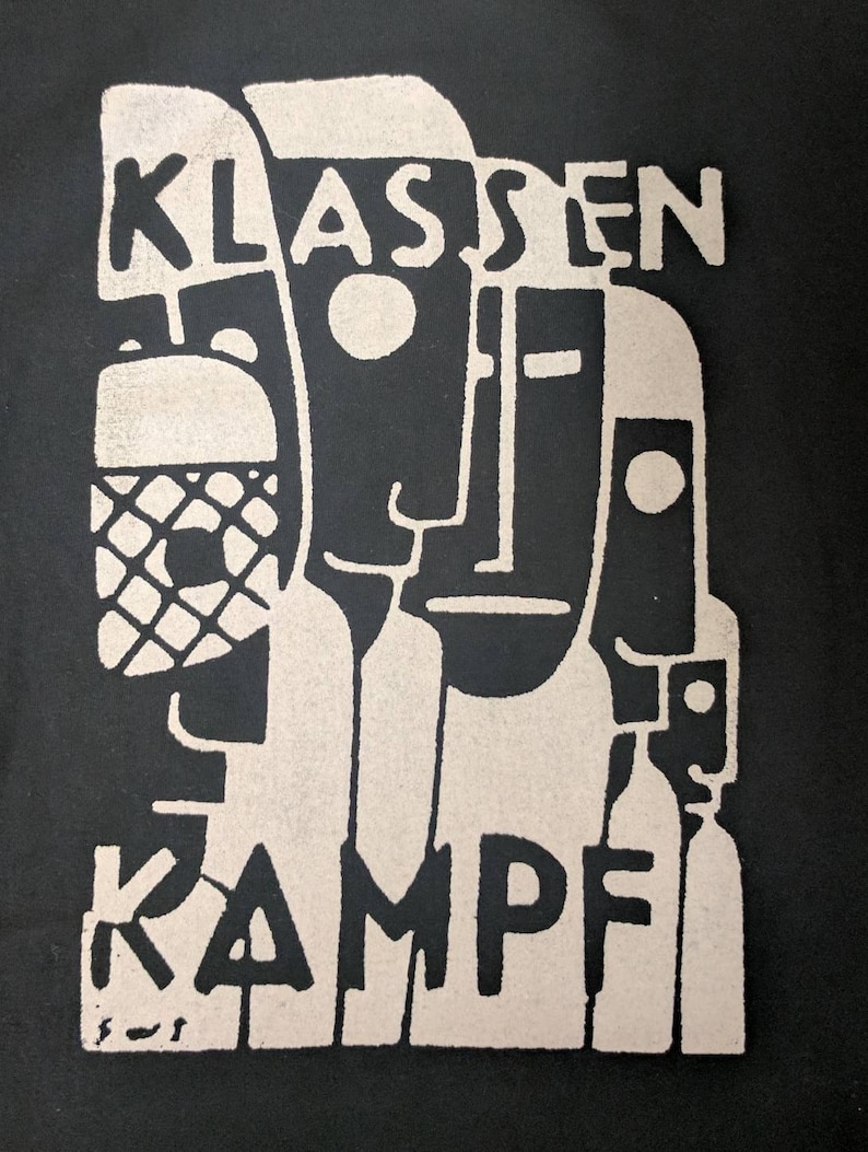 May include: Black and white graphic print with the text "KLASSEN KAMPF" in a bold, stylized font. The design features abstract figures with geometric shapes.