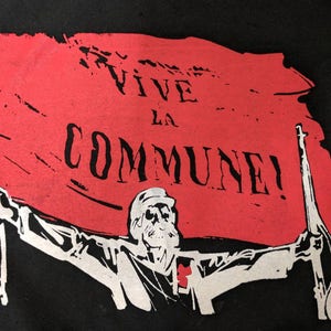 May include: A black and white illustration of a person holding a red flag with the text "VIVE LA COMMUNE!" printed on it.
