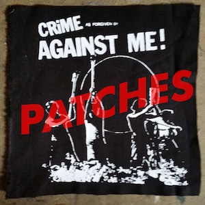 May include: Black and white patch with the text "Crime as forgiven by Against Me!" and the word "Patches" in red letters over a graphic of three figures holding a hoop.