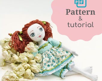 May include: A PDF pattern and tutorial for making a handmade doll. The doll has red hair, a blue and white dress, and is lying on a bed of white flowers.