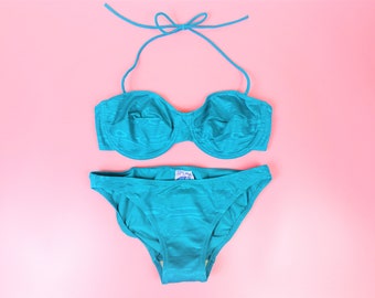 May include: A turquoise blue bikini with a halter top and a high-waisted bottom. The bikini is made of a shiny, textured fabric.