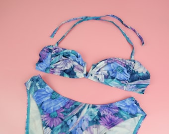 Könnte beinhalten: Ein Bikini mit Blumenmuster, einem Neckholder-Oberteil und einem hoch sitzenden Unterteil. Das Oberteil hat einen V-Ausschnitt und das Unterteil einen vollständigen Rücken.