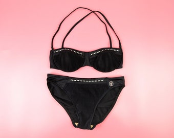 Könnte beinhalten: Schwarzer Bikini mit schwarzem und weißem Besatz. Das Oberteil ist im Bandeau-Stil und das Unterteil im hochgeschnittenen Stil.