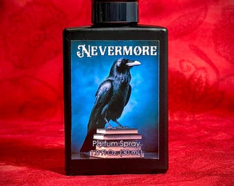 May include: A rectangular black glass perfume bottle with a black cap. The front label features a black raven perched on a stack of books against a blue background, with the text NEVERMORE, Parfum Spray, and 1.0 Fl Oz. (30 mL) printed on it.
