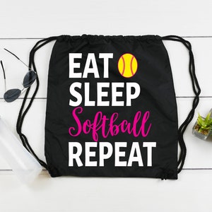 May include: Black drawstring bag with white text that reads "Eat Sleep Softball Repeat" and a yellow softball graphic.