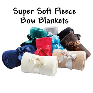 A graphic showing the colors of the super soft fleece blankets we offer:  vanilla, tan, blue, brown, black, and gray.  All come with a matching decorative satin ribbon with hook & loop closure for easy gifting and/or quick storage.  This fleece throw makes a great gift.