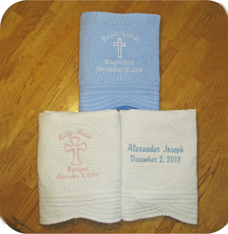 Pode incluir: Tr&ecirc;s mantas de beb&ecirc; bordadas, uma azul claro com bordados brancos, uma branca com bordados rosa e uma branca com bordados azuis. As mantas s&atilde;o personalizadas com nomes e datas. O texto nas mantas diz: "Noah Luck Batizado em 18 de novembro de 2018", "Kelly Marie Batizada em 3 de novembro de 2018" e "Alexander Joseph em 2 de dezembro de 2018".