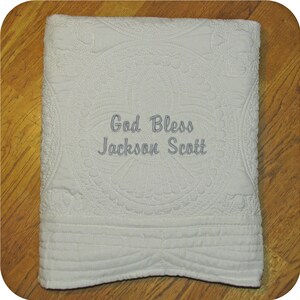 Pode incluir: Cobertor de beb&ecirc; acolchoado branco com um design bordado branco e o texto "God Bless Jackson Scott".