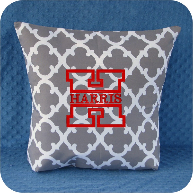 May include: A gray and white patterned pillow with a red embroidered letter H and the name HARRIS.