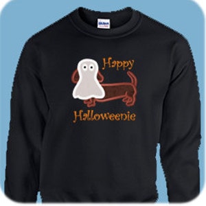 May include: Black sweatshirt featuring a brown dachshund wearing a white ghost costume. The text "Happy Halloweenie" is embroidered in orange on the sweatshirt.