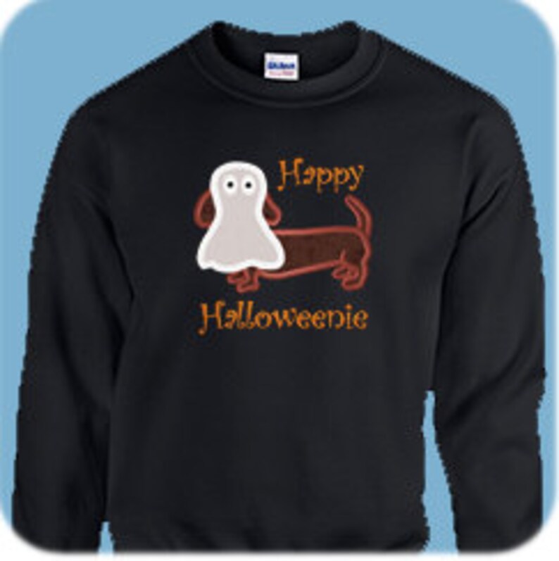 May include: Black sweatshirt featuring a brown dachshund wearing a white ghost costume. The text "Happy Halloweenie" is embroidered in orange on the sweatshirt.