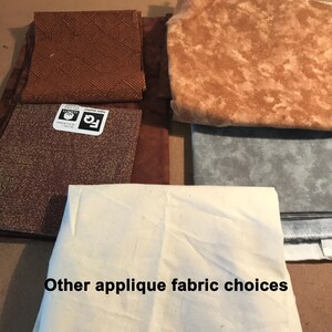 May include: A collection of fabric squares in various shades of brown, gray, and off-white. The pieces feature different textures and patterns, including a woven design and mottled prints. One square has a label reading FQ 18 x 21 inches.