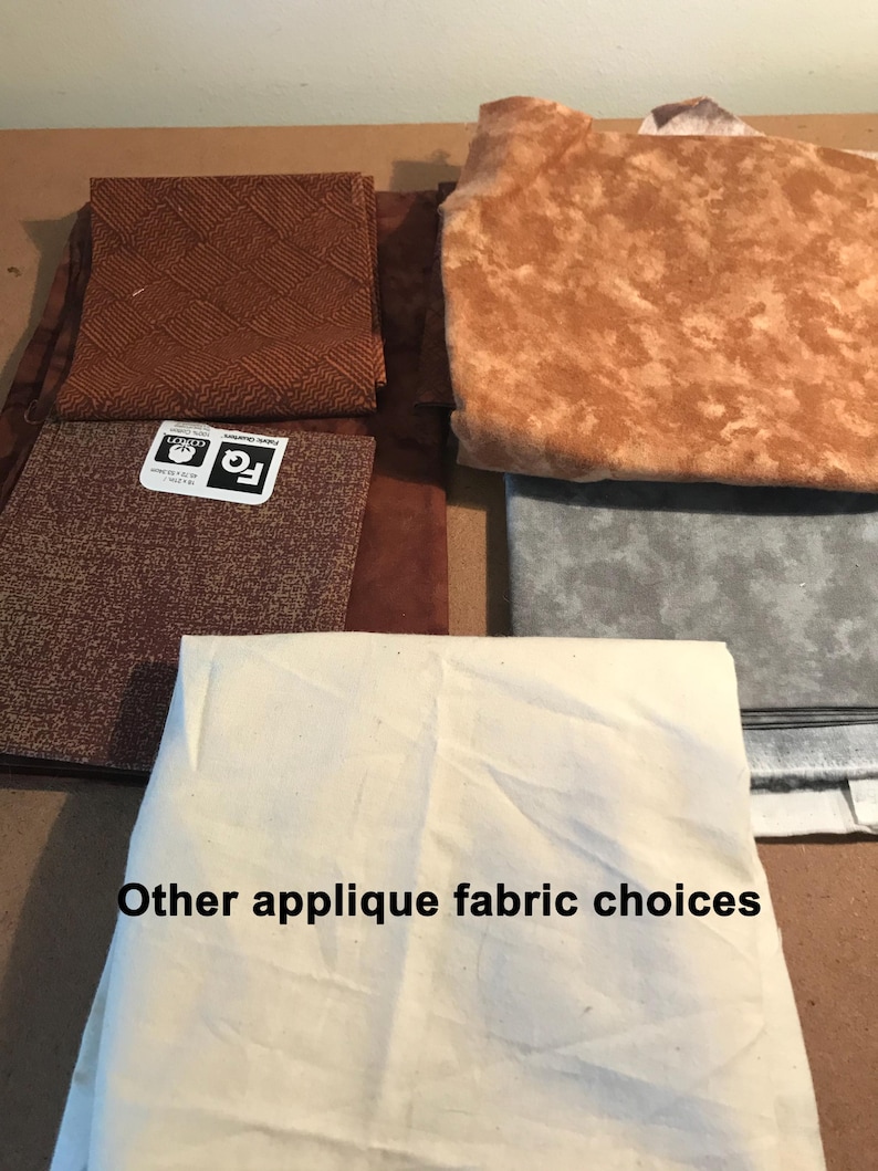May include: A collection of fabric squares in various shades of brown, gray, and off-white. The pieces feature different textures and patterns, including a woven design and mottled prints. One square has a label reading FQ 18 x 21 inches.