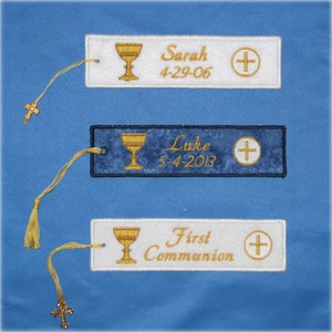 May include: Embroidered bookmarks with gold chalice and cross designs. One bookmark is blue with "Luke 5-4-2013" text, and two are white with "Sarah 4-29-06" and "First Communion" text. Each has a gold tassel and cross charm.