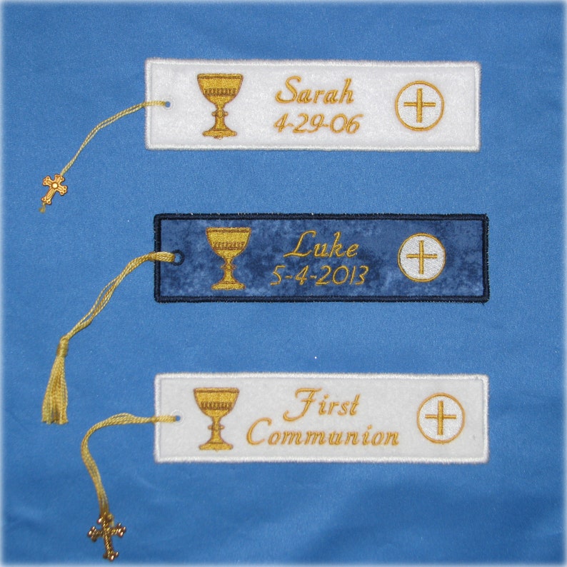 May include: Embroidered bookmarks with gold chalice and cross designs. One bookmark is blue with "Luke 5-4-2013" text, and two are white with "Sarah 4-29-06" and "First Communion" text. Each has a gold tassel and cross charm.