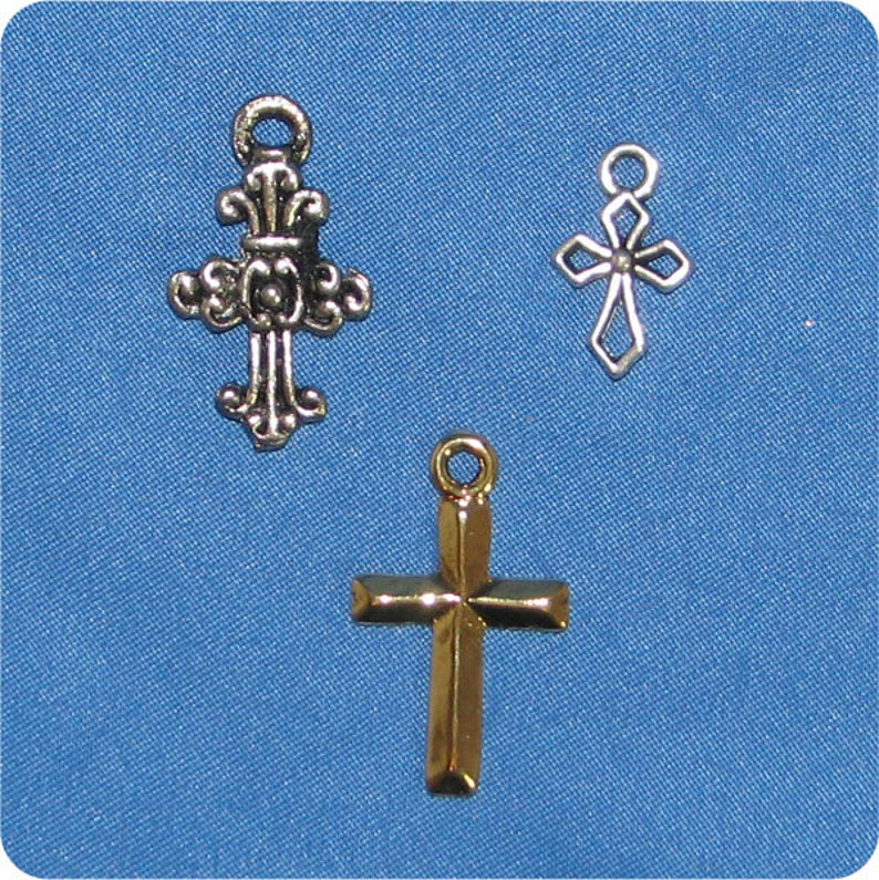 May include: Three metal cross charms in different designs. One is ornate and silver, another is a simple openwork silver cross, and the third is a gold-colored cross with a classic shape. All have loops for attaching to jewelry.