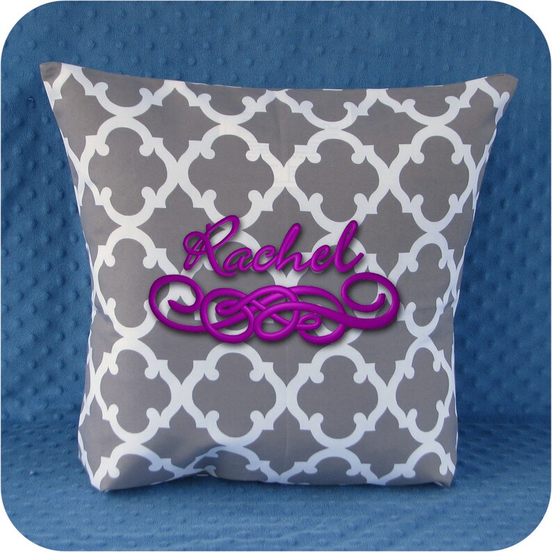 May include: Gray and white patterned pillow with the name "Rachel" embroidered in purple.