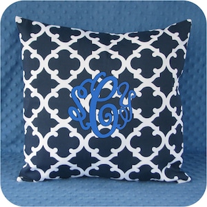 May include: A navy blue and white patterned throw pillow with a blue monogram in the center.
