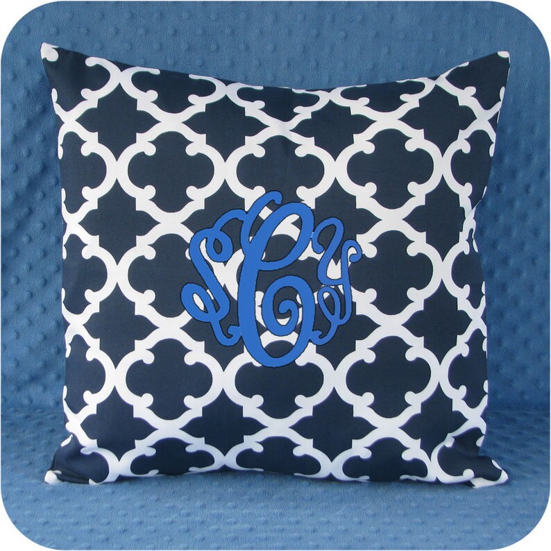 May include: A navy blue and white patterned throw pillow with a blue monogram in the center.