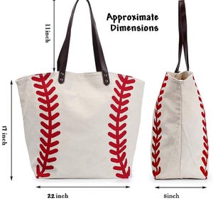 May include: A cream-colored canvas tote bag with a red baseball stitch pattern, dark brown leather straps, and metal rivets. The bag measures 17 inches in height, 22 inches in width, and 8 inches in depth, with an 11-inch strap drop height.