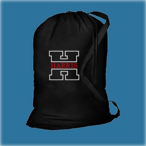 A black drawstring cotton or canvas laundry bag with a white outlined capital H and the word 'HARRIS' in red thread inside the letter.