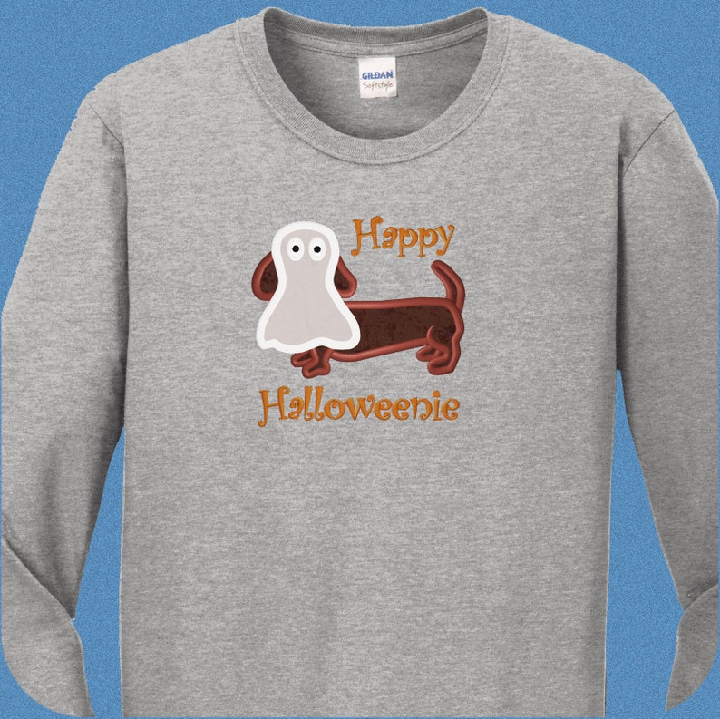 May include: A grey long-sleeved t-shirt with a brown dachshund wearing a white ghost costume. The text "Happy Halloweenie" is printed on the shirt.