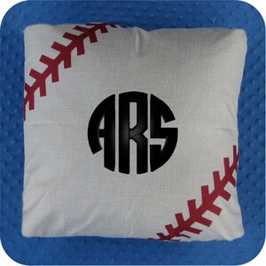 Puede incluir: Una almohada blanca con un dise&ntilde;o de puntadas de b&eacute;isbol rojas y un c&iacute;rculo negro con las letras "ARS" en el centro.
