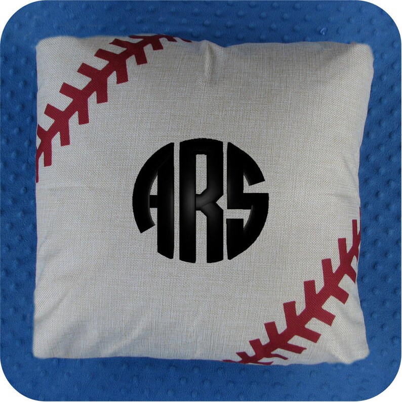 Puede incluir: Una almohada blanca con un dise&ntilde;o de puntadas de b&eacute;isbol rojas y un c&iacute;rculo negro con las letras "ARS" en el centro.