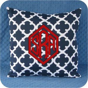 May include: A navy blue and white patterned throw pillow with a red monogram in a hexagonal shape. The monogram reads "SRA".