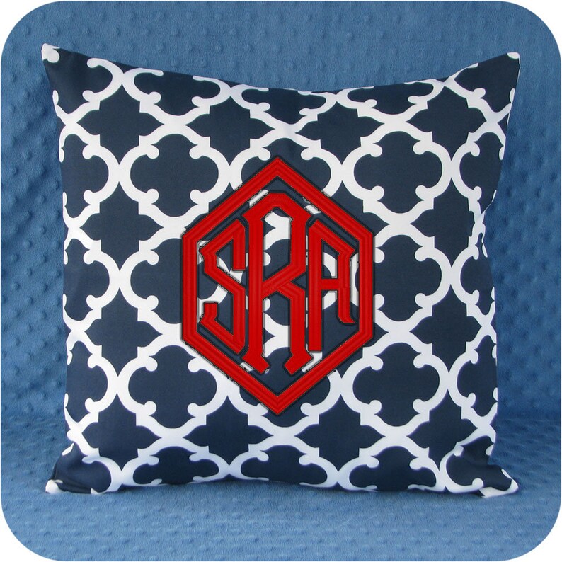 May include: A navy blue and white patterned throw pillow with a red monogram in a hexagonal shape. The monogram reads "SRA".