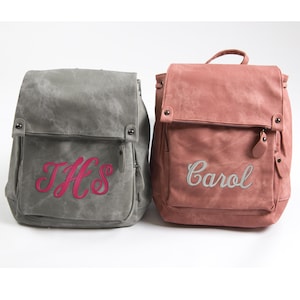 May include: Two personalized backpacks, one gray with pink embroidery that says "THS" and one pink with gray embroidery that says "Carol".