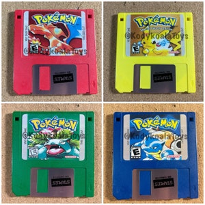 May include: Four 3.5-inch floppy disks with Pokemon game covers. The disks are red, yellow, green, and blue. Each disk has a different Pokemon character on the cover. The text on the disks reads "Pokemon" and "Special Pikachu Edition".