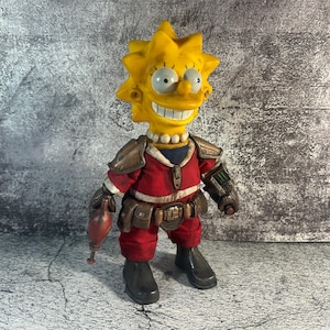 Puede incluir: Una figura de acción personalizada de Lisa Simpson con un atuendo rojo y marrón, con una cabeza amarilla y pelo puntiagudo. La figura tiene un disfraz detallado con un cinturón de herramientas, armadura y botas negras. La figura está sobre una superficie gris.