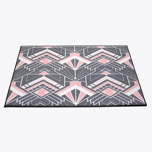 May include: A geometric patterned doormat with a black border. The pattern features pink, white, and gray geometric shapes.