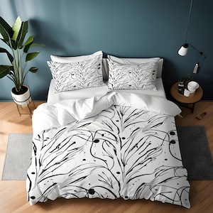 May include: White duvet cover with a black and white abstract floral pattern. The duvet cover is on a bed with two matching pillowcases.