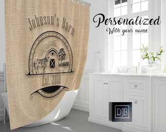 May include: A brown burlap shower curtain with a black and white design of a barn, a cow, and a pig. The text "Johnson's Barn Est. 2018" is printed on the curtain.