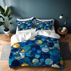 May include: A blue and yellow duvet cover with a pattern of abstract circles. The duvet cover is on a bed with white pillows and a white bedspread.