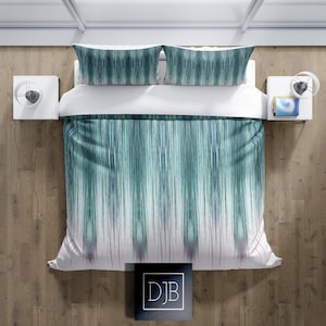 May include: A white duvet cover with a teal and blue abstract pattern. The duvet cover is on a bed with two matching pillowcases.
