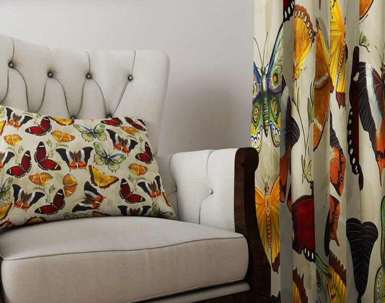 May include: A white armchair with a tufted back and a pillow featuring a colorful butterfly pattern. The armchair is in front of a curtain with a similar butterfly pattern.