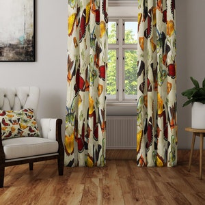 May include: A pair of cream-colored curtains with a colorful butterfly print. The curtains feature a variety of butterfly designs in shades of red, orange, yellow, green, and blue.