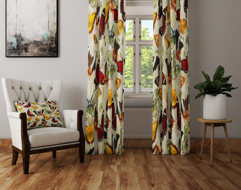 May include: A pair of cream-colored curtains with a colorful butterfly print. The curtains feature a variety of butterfly designs in shades of red, orange, yellow, green, and blue.