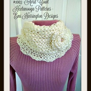 Könnte beinhalten: Ein weißer Häkelkragen mit einem weißen Häkelblumen-Akzent. Der Kragen wird über einem rosa Pullover getragen. Der Text #1003 - Avril Cowl  Heetanooga Patterns - Emi Harrington Designs ist im Bild sichtbar.
