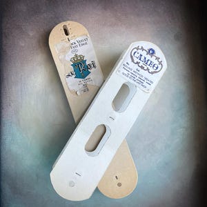 May include: Two vintage fabric tags. One is tan with the text "Black Velvet Fast Edge" and "Roi" with a crown emblem. The other is white with the text "Cameo" and "Reeling Method Treated". Both tags have cut-out sections.