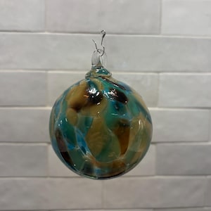 Adorno navideño de vidrio soplado a mano, en beige, marrón, verde azulado y crema. Hecho a mano en las montañas Ozark. Nuevo color para 2026. Nombre del color: Adoquín. imagen 1