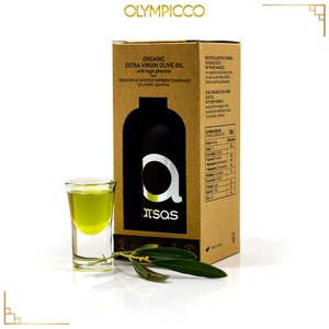 Puede incluir: Una caja de cart&oacute;n marr&oacute;n con una etiqueta blanca que dice "ORGANIC EXTRA VIRGIN OLIVE OIL with high phenols". La caja est&aacute; sobre una superficie blanca con un peque&ntilde;o vaso de chupito de vidrio lleno de aceite de oliva y una rama de olivo verde.