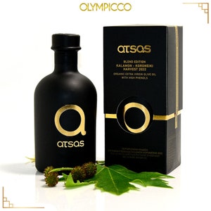 Puede incluir: Un juego de botella y caja de aceite de oliva negro con letras y detalles dorados. La botella y la caja presentan la marca "atsas" y el texto "BLEND EDITION KALAMON-KORONEIKI HARVEST 2022 ORGANIC EXTRA VIRGIN OLIVE OIL WITH HIGH PHENOLS."