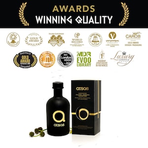 K&ouml;nnte beinhalten: Schwarze Oliven&ouml;lflasche und -box mit goldenen Akzenten. Die Flasche hat ein goldenes "a"-Logo und die Box den Markennamen "atsas". Das Bild enth&auml;lt den Text "Awards Winning Quality" und mehrere goldene Auszeichnungen.